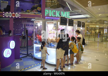 Die Spieler greifen Puppen auf gewöhnliche Puppe - grabbing Maschinen mit einer Shopping Mall in Shanghai, China, 7. August 2018. Ein 2-stöckiges riesigen menschlichen Puppe - ergreifende m Stockfoto