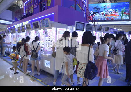 Die Spieler greifen Puppen auf gewöhnliche Puppe - grabbing Maschinen mit einer Shopping Mall in Shanghai, China, 7. August 2018. Ein 2-stöckiges riesigen menschlichen Puppe - ergreifende m Stockfoto