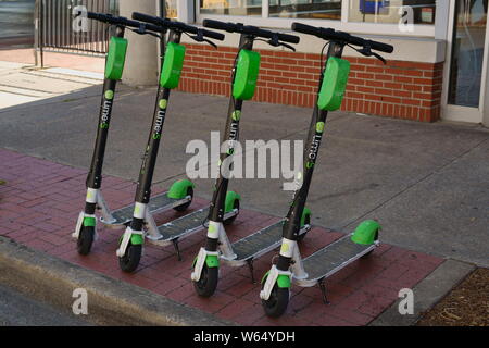 Dockless Elektroroller aufgereiht auf dem Bürgersteig in Little Rock, Arkansas, USA. Kalk - S elektrische Motorroller mieten. Stockfoto