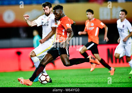 Senegalesischer Fußballspieler Makhete Diop, rechts, von Peking Renhe passt den Ball gegen die serbischen Fußball-Spieler Nemanja Pejcinovic von Changchun Yatai Stockfoto