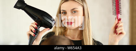 Blonde Hairstylist mit Fön und Kamm Stockfoto