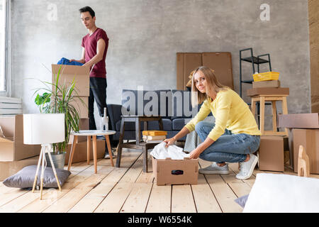 Glücklich lächelnde Paar Umzug in ein neues Haus und Auspacken der Kartons Kartons, Umzug und Renovierung Konzept Stockfoto