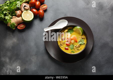 Tom Yam kung Würzige Suppe mit Garnelen, Meeresfrüchte, Tomaten, Pilze, Kokosmilch, Zitronengras, Ingwer und Chili Pfeffer in der Schüssel. Traditionelle thailändische Küche Stockfoto