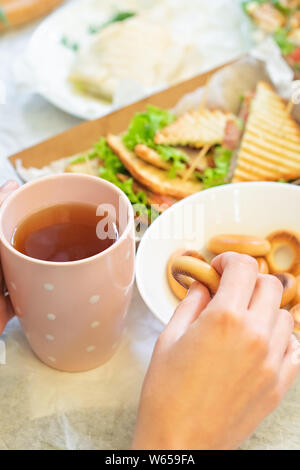 Weibliche Hände mit einer Tasse Kaffee und Bagels. Stockfoto