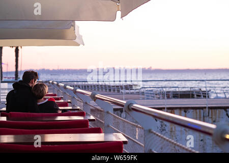 Paar am Ufer des Sees erfüllt die Morgenröte. Junge und Mädchen an der Küste. Für den Sonnenaufgang am Meer. Hochzeitsreise. Der Mann und die Frau vom Meer Stockfoto