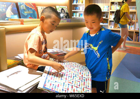 ---- Kinder lesen Bücher in einer Buchhandlung in Peking, China, 15. August 2018. Twilight Funkeln, Solitärspiele und die Schlümpfe sind populäre Bücher, coul Stockfoto