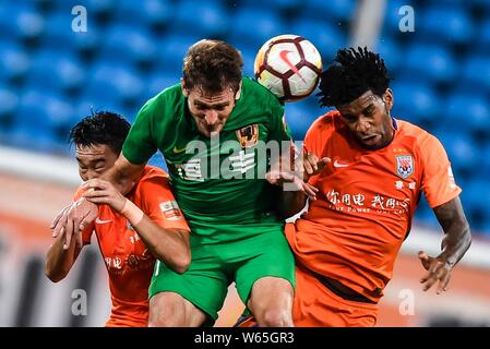 Kroatischer Fußballspieler Nikica Jelavic, Mitte, von Guizhou Hengfeng Köpfe die Kugel ein Pass gegen den brasilianischen Fußballspieler Gil von Shandong Lun zu machen Stockfoto