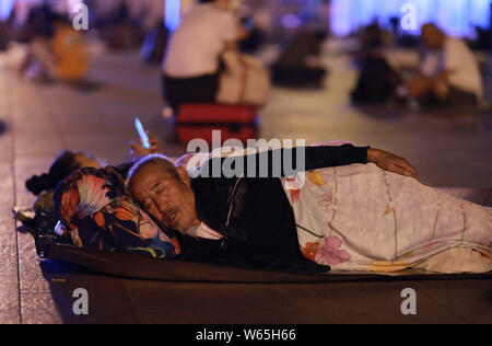 Einen chinesischen Pkw schläft und wartet auf seinen Zug auf dem Platz der Beijing Railway Station in Peking, China, 18. August 2018. Chinesische Passagiere sl Stockfoto