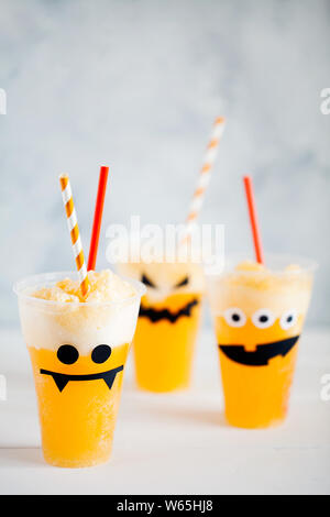 Dekorierte Gläser mit kalten Kürbis orange Cocktail (Punch, Limonade, Schütteln, Smoothie) mit netten, lustigen und gruseligen Gesicht für Halloween mit Kopie Raum Stockfoto