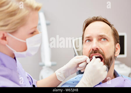 Zahnarzthelfer bildet das Flossing eine professionelle Zahnreinigung bei einem Patienten Stockfoto