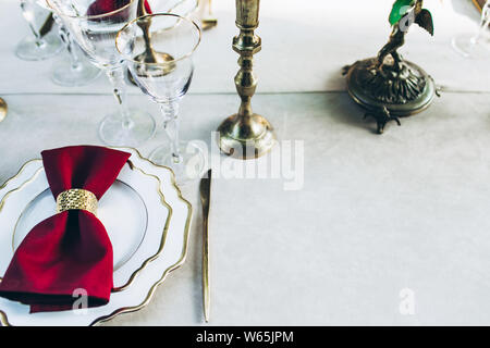 Überblick über ein schön serviert Abendessen mit goldenen Messern, Weingläser, Kerzen. Stockfoto