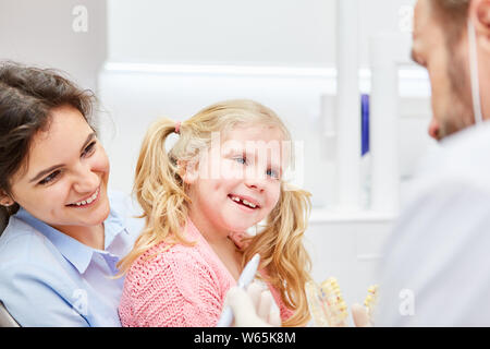 Lächelnd Kind als Angst Patienten Vertrauen zu dem Kind Zahnarzt auf dem Schoß der Mutter Stockfoto