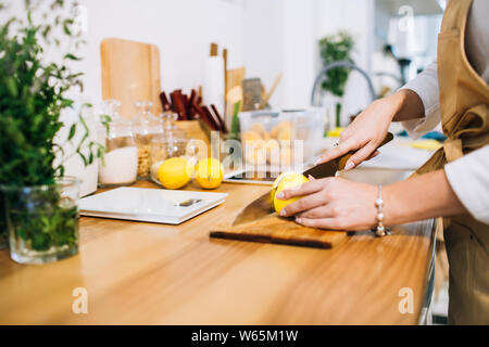 Weibliche Hände die Zitrone mit einem scharfen Messer in einem hellen minimalistische Küche, immer bereit für das Kochen. Stockfoto