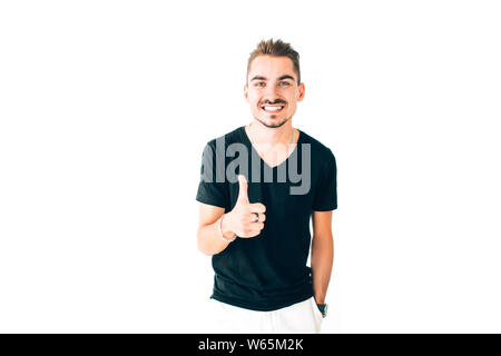 Gerne fröhliche junge Mann in einem schwarzen T-Shirt, Daumen hoch, auf weißem Hintergrund. Stockfoto