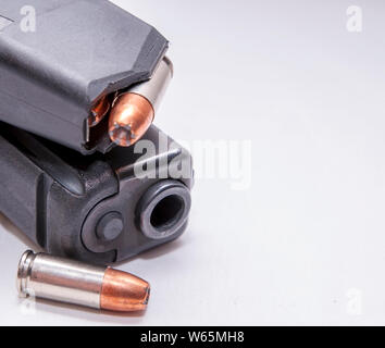 Ein schwarzes 9-mm-Pistole mit einer geladenen Magazin auf Sie und einer einzigen 9 mm Hollow point bullet Weiter, um es auf einem weißen Hintergrund Stockfoto