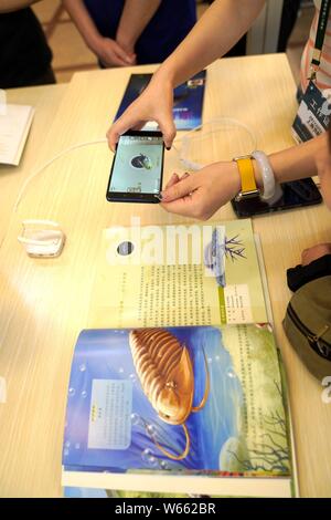 ---- Eine Chinesische Benutzer von Mobiltelefonen verwendet Ihr Smartphone für AR Lesung während der Buchmesse Shanghai in Shanghai, China, 17. August 2017. Mobile lesen Stockfoto