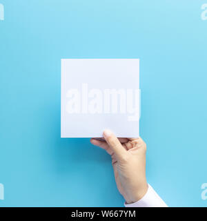 Frau Hand, leeres Blatt Papier auf blauem Hintergrund mit Kopie Raum isoliert. Stockfoto