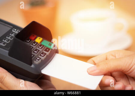 Zahlung mit Kreditkarte Konzept. close-up Hand credit card ein mock up mit weißen leere Karte mit einer Karte streichen Maschine am Point of Sale Terminal in Cof Stockfoto