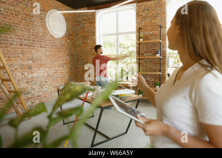 Junges Paar Wohnung Reparatur zusammen selbst machen. Verheirateten Mann und Frau tun Home Makeover oder Renovierung. Konzept der Beziehungen, Familie, Liebe. Überprüfung erfolgen Design, neue Möbel. Stockfoto