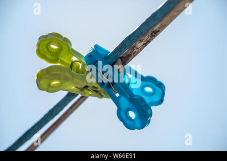 Wäscheklammern hängend an einem Seil gegen den blauen Himmel. Zwei Wäscheklammern hängend an einem Seil im Freien. Stockfoto