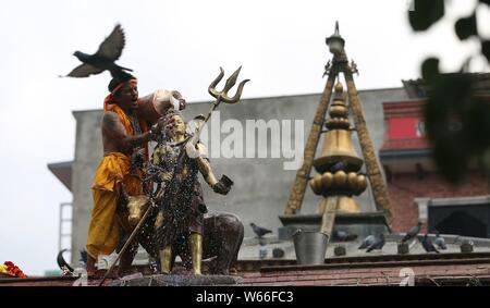 Kathmandu, Nepal. 31. Juli 2019. Ein hinduistischer Priester gießt Milch zum Idol von Lord Shiva an der Shiva Tempel in Kathmandu, Nepal, 31. Juli 2019. Der heilige Monat Shrawan ist auspicious von Hindus für das beten zu Gott Shiva für Glück und Wohlstand. (Foto von Sunil Sharma/Xinhua) Quelle: Xinhua/Alamy leben Nachrichten Stockfoto