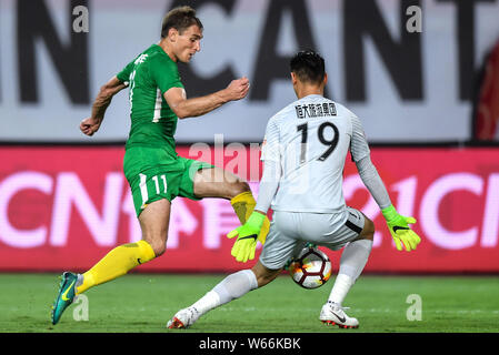 Kroatischer Fußballspieler Nikica Jelavic, links, von Guizhou Hengfeng Schüssen den Ball gegen einen Spieler von Guangzhou Evergrande Taobao in Ihren 12 ma Stockfoto