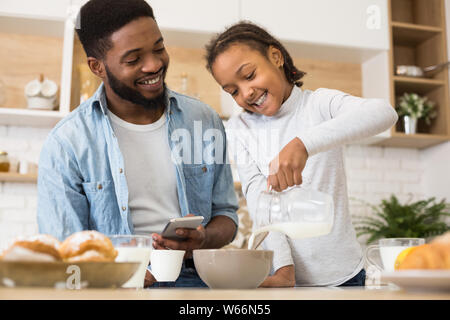 Süße kleine Mädchen Milch in die Schüssel mit Cornflakes gießen Stockfoto