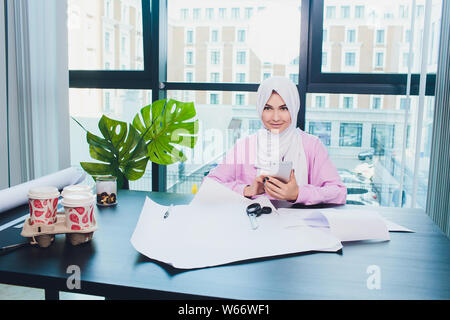 Porträt der jungen attraktiven muslimische Frau Mode Designer in ihrer Werkstatt lächeln in die Kamera. Stockfoto