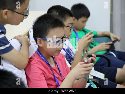 ---- Kurzsichtige Kinder tragen Brillen Videospiele auf Smartphones in Zhengzhou City spielen, der Central China Provinz Henan, 17. Juli 2018. Ein Stockfoto