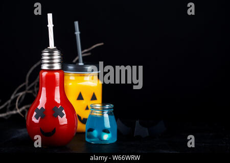 Halloween gesund Kürbis und Tomatensaft im Glas, künstliche Augäpfel in eine blaue Flüssigkeit auf einem dunklen Hintergrund mit Kopie Raum Stockfoto