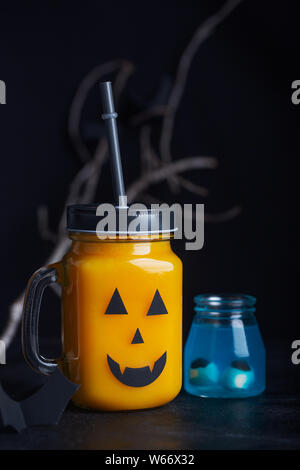Halloween gesund Kürbis oder Karotte Getränke im Glas, künstliche Augäpfel in eine blaue Flüssigkeit auf schwarzem Hintergrund Stockfoto