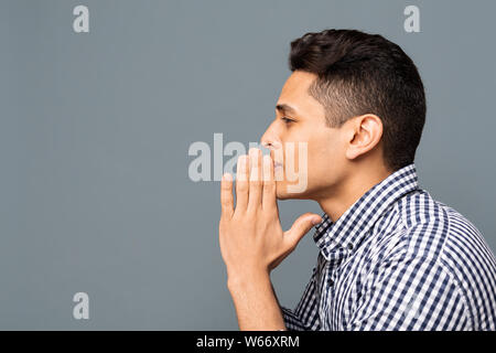 Junger Mann beten und bitten um etwas, Seitenansicht Stockfoto