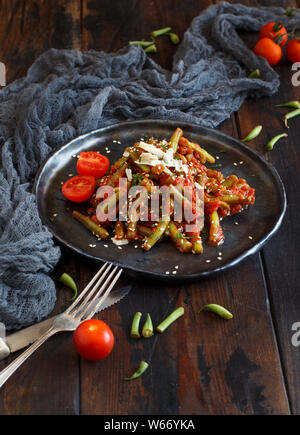 Bohnen mit Tomaten Eintopf in der Nähe auf einem dunklen Tabelle Stockfoto