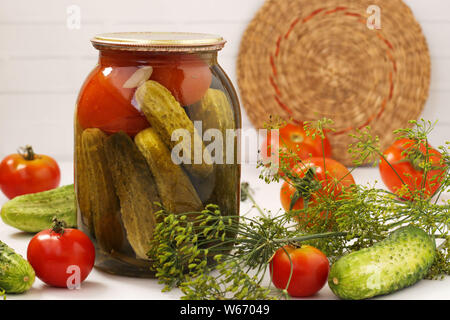 Marinierten Gurken mit Tomaten, die in Gläsern auf einem weißen Hintergrund befinden, Ernte für den Winter, Nahaufnahme, horizontale Foto Stockfoto