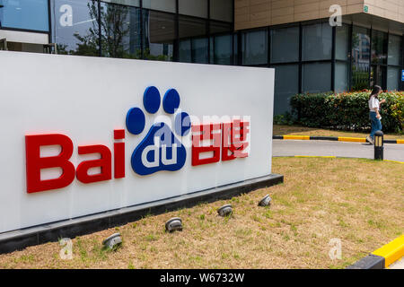 ---- Ein Fußgänger geht vorbei an einer Tafel von Baidu auf ein Bürogebäude in Shanghai, China, 26. Juni 2018. Baidu und BMW haben eine Vereinbarung unterzeichnet. Stockfoto