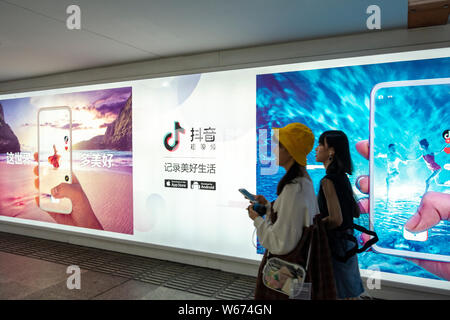 ---- Fußgänger vorbei an eine Werbung für die mobile App von Tik Tok, einer im Ausland Iteration von kurzen Video app Douyin, von Peking Bytedance Te Stockfoto