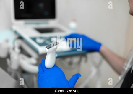 Ein Tierarzt tut ein Ultraschall der Auge des Hundes im Büro. Der männliche Arzt Hand auf dem Ultraschallgerät. Ultraschall Sensor in Doctor's Hand clo Stockfoto