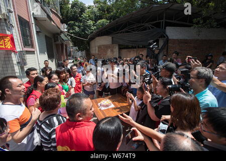 Zhong Fengmin, ihre amerikanischen und chinesischen Familie, freiwillige Helfer und Polizisten teilen sich einen Kuchen in Guangzhou City, die südchinesische Provinz Guangdong, 3 Jun Stockfoto