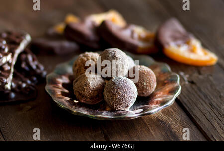 Schokolade, Trüffel und Orangenscheiben in dunkler Schokolade auf einem Holztisch Stockfoto