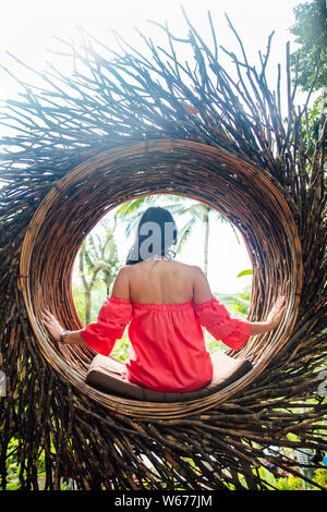 Eine weibliche Touristen sitzen auf einem großen Vogelnest auf einem Baum an der Insel Bali, Indonesien Stockfoto