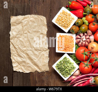 Hülsenfrüchte in Schalen, Gemüse und Papier auf einem Holztisch Stockfoto