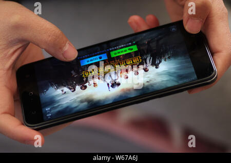 ---- Eine Chinesische mobile Game Player spielt's Tencent multiplayer Online Battle Royale's Spiel PlayerUnknown Schlachtfelder, auf sein Smartphone in Ji'nan Stockfoto