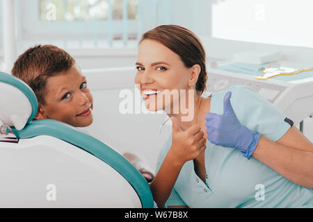 Cute Boy und positive weibliche Zahnarzt mit Daumen nach oben. Kind zahnmedizinische Behandlung Stockfoto