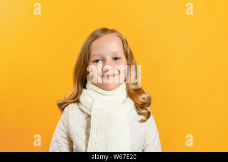 Porträt eines niedlichen kleinen Mädchen in einer Jacke und Schal über einen gelben Hintergrund. Herbst Konzept. Kopieren Sie Platz. Stockfoto