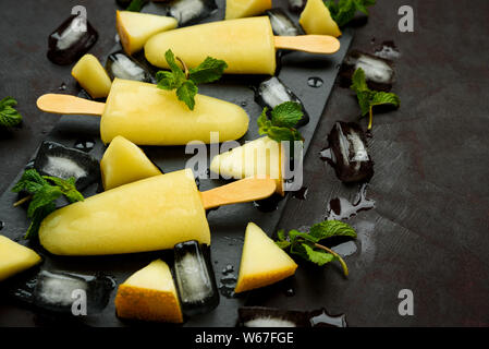 Hausgemachte melone Eis, Pops oder Eis am Stiel mit Eis, Melone Schichten und Minze auf rechteckige Dunkle Schiefer Platte. Im Sommer essen. Flach. Ansicht von oben Stockfoto