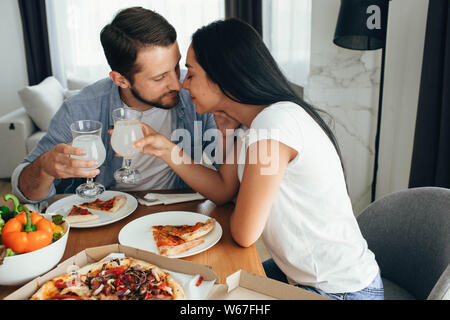 Glückliches Paar küssen und ein Abendessen mit Pizza zu Hause. Es ist eine gute Zeit verbringen Home Stockfoto