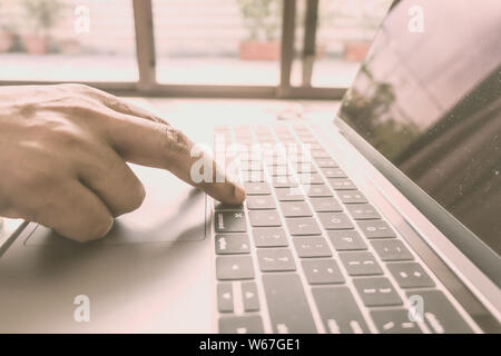 Nahaufnahme der männlichen Händen mit Laptop im Büro, sich die Hände des Mannes mit der Eingabe auf Laptop Tastatur. Close-up. Vintage Style. Kopieren Raum Platz für Text. Stockfoto