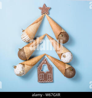 Weihnachtsbaum aus Eistüten und festliche Weihnachten Kugeln mit Ingwer Cookies auf einer hellen blauen Hintergrund. Ansicht von oben, flach Stockfoto