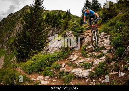 MORZINE, Frankreich. Ein Mountainbiker, eine schwierige Rocky alpine Trail mit Wald und Felsen im Hintergrund. Stockfoto