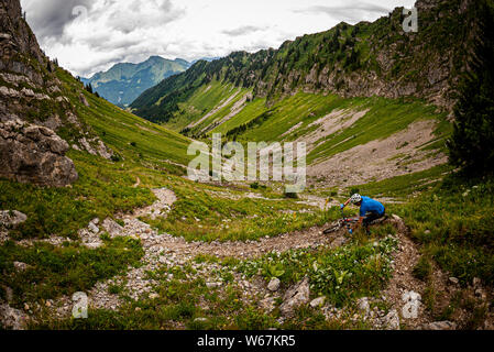 MORZINE, Frankreich. Ein Mountainbiker, eine felsige, kurvenreiche alpine Trail hinunter eine große V-förmige' Tal mit Klippen und alpine mounatins im b Stockfoto